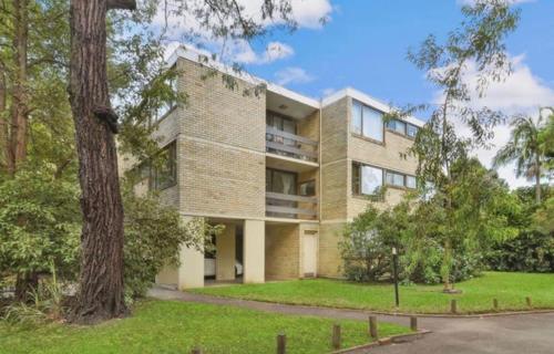 a large brick building with a tree in front of it at Stylish 1-Bedroom Apartment in the Heart of Cremorne in Sydney