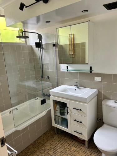 a bathroom with a sink and a toilet and a shower at Stylish 1-Bedroom Apartment in the Heart of Cremorne in Sydney