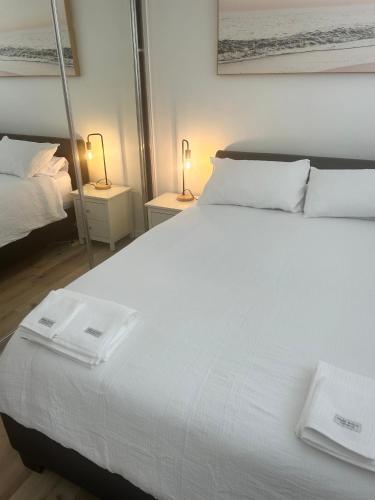 a bedroom with a large white bed with two lamps at Stylish 1-Bedroom Apartment in the Heart of Cremorne in Sydney