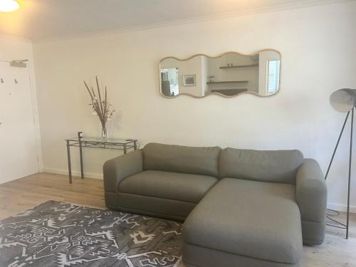 a living room with a couch and a mirror at Stylish 1-Bedroom Apartment in the Heart of Cremorne in Sydney
