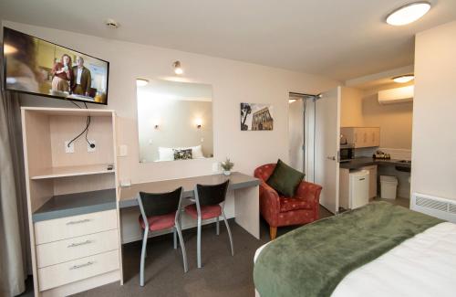 a bedroom with a bed and a desk and chairs at Cranford Oak Motel in Christchurch
