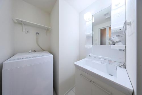 a white bathroom with a sink and a washing machine at とりっぱーずホテル方南町 in Tokyo