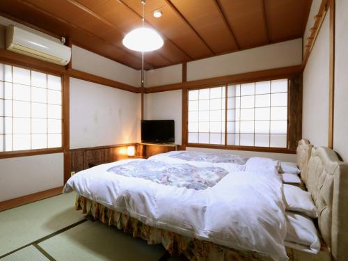 a bedroom with a large bed in a room with windows at Villa Izumoya in Izumo