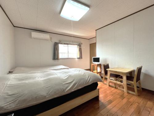 a bedroom with a bed and a table and a desk at ウィークリー宿家里 in Akaren