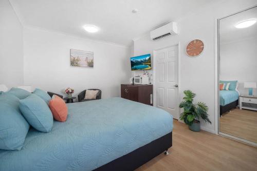 a bedroom with a blue bed and a mirror at Waterfront Studio Room Near City Stadium & Ferry in Townsville in Townsville