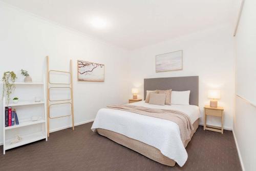 a white bedroom with a bed and two shelves at Prime Position for City and Stadium Access in Townsville