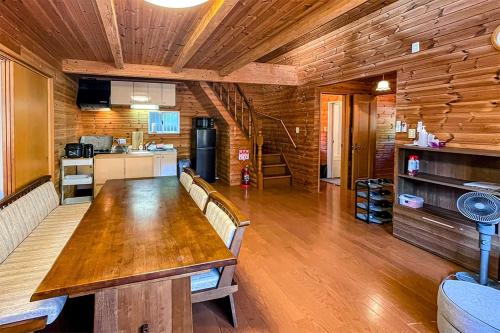 a dining room with a wooden table and a kitchen at るり渓フォレストコテージｂ-9号棟樋口邸 in Nantan city