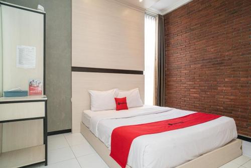 a bedroom with a bed with a brick wall at RedDoorz Syariah At Mitra Guest House in Malang