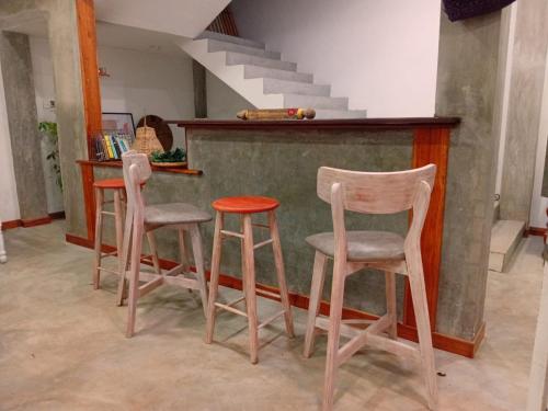 a kitchen with three stools and a counter with stairs at Villa De'YuLee in Negombo