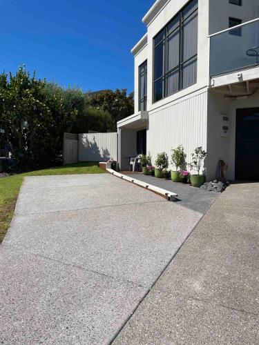 a driveway leading to a white building with plants at Quiet restful unit with seaviews in Auckland