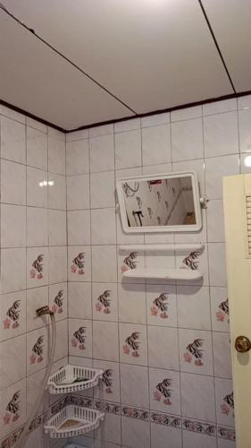 a bathroom with a mirror on a tiled wall at Lanta Diamond in Ko Klang