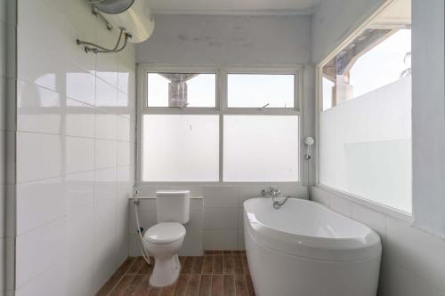 a white bathroom with a toilet and a window at RedDoorz Plus @ Vantas Hotel Parbaba in Sinapuran