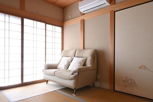 a living room with a white couch and windows at Villa Izumi Eternity and a Day 一棟貸し民泊いずみの宿永遠と一日 in Izumi