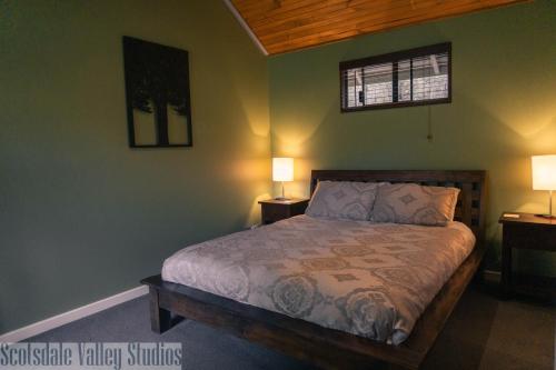 a bedroom with a bed with two night stands and two lamps at Scotsdale Valley Studios in Harewood