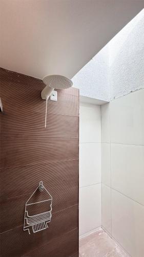 a bathroom with a wooden wall and a ceiling at Suítes Santorini | The Férias - Aconchego no Centro de Arraial do Cabo com Cozinha Compartilhada e AR in Arraial do Cabo