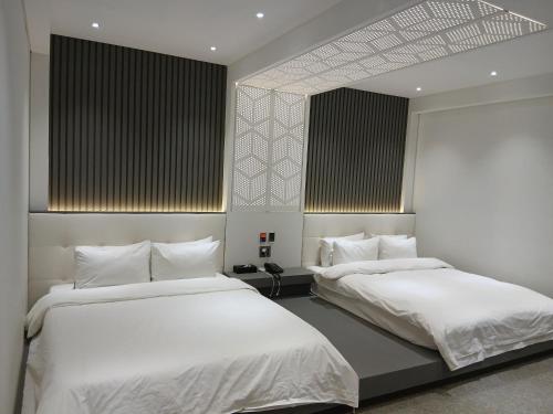 two beds in a room with white sheets at 부산파크호텔 in Busan