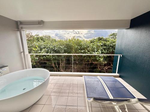 a bathroom with a bath tub and a balcony at Plus Life Shiraho A号室 in Ishigaki Island
