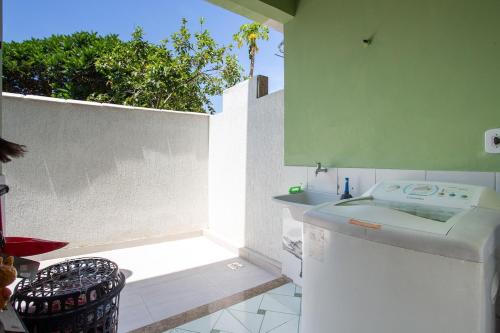 a white bathroom with a sink and a wall at Casa de Vila Duplex, perto do Centro in Araruama