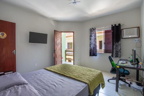 a bedroom with a bed and a desk and a window at Casa de Vila Duplex, perto do Centro in Araruama