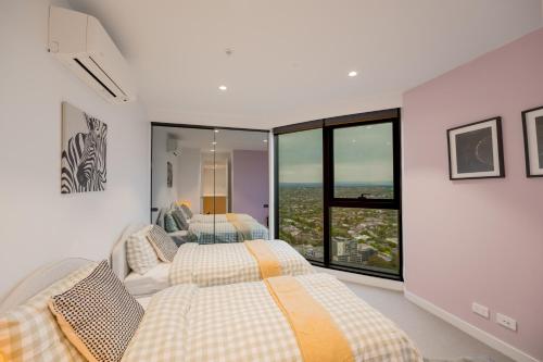 two beds in a bedroom with a window at Sky One Grand Terrace Penthouse in Box Hill