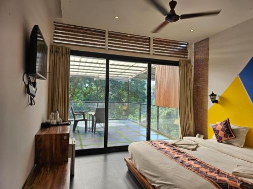 a bedroom with a bed and a balcony with a table at Hillora Coastal Resort in Arpora