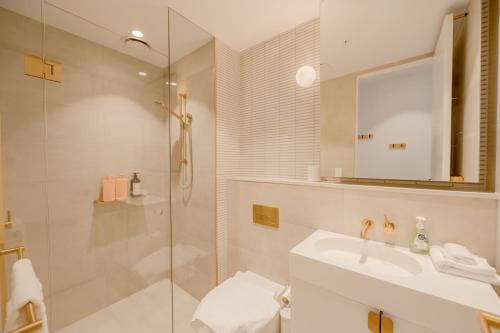 a bathroom with a shower and a sink and a mirror at Sky One Grand Terrace Penthouse in Box Hill