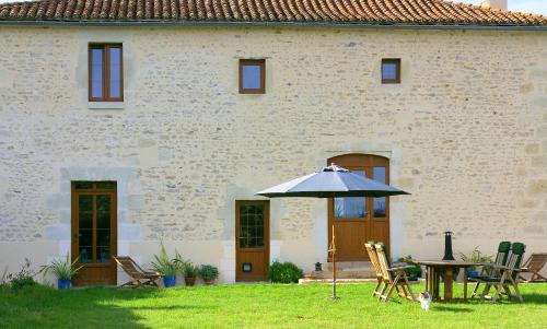 a table with an umbrella in front of a building at Chambre d'Hôtes Oiron, Deux Sevres - not near Taize, Burgundy in Oiron