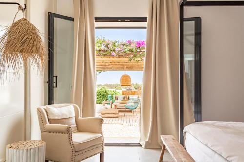 a bedroom with a bed and a chair and a patio at Villa Charming House in La Mola