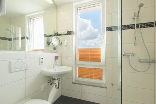 a bathroom with a sink and a toilet and a window at Hotel Meridian ***superior in Landshut