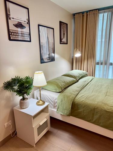 a bedroom with a bed and a plant on a night stand at The Vibe BGC Uptown Apartment in Manila