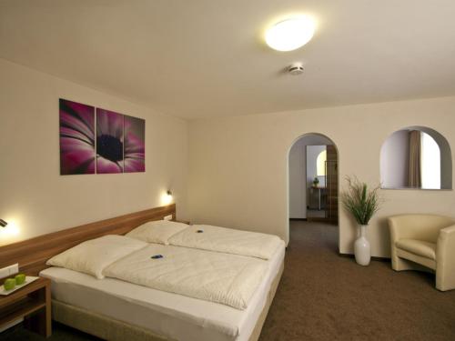 a bedroom with a large bed and a chair at Hotel Sielminger Hof in Filderstadt