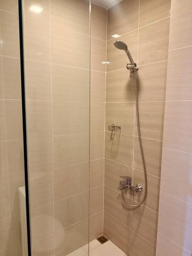 a shower with a glass door in a bathroom at The Vibe BGC Uptown Apartment in Manila