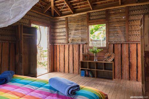 a bedroom with a bed in a room with wooden walls at Fanifo Lofa in Ha’apai