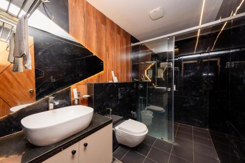 a bathroom with a sink and a toilet and a shower at THE CONTINENTAL INN & SUITES in Mysore