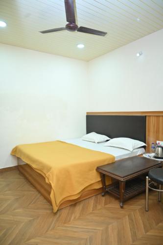 a bedroom with a bed and a table and a ceiling at Hotel aditya palace in Padrauna