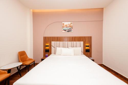 a bedroom with a large bed and two chairs at THE CONTINENTAL INN & SUITES in Mysore