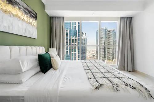 a bedroom with a white bed and a large window at Spectacular Studio & 1 Bedroom Apartments in Dubai