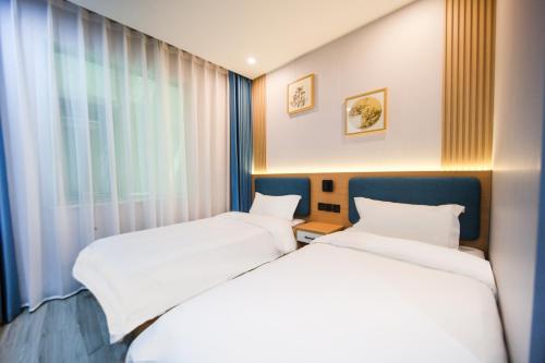 two beds in a room with a window at 晨雷酒店 in Beijing