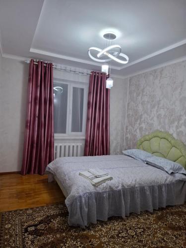 una camera da letto con un letto con tende rosse e un soffitto di Квартира a Karakol