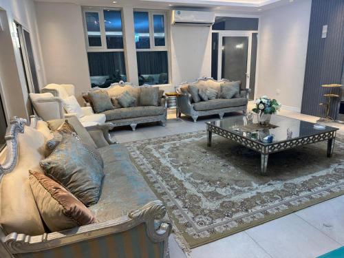 a living room with couches and a coffee table at Huge luxury villa stay with private room in Ajman
