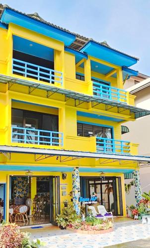 a yellow building with blue balconies at Lanta MP Place - Adult Only in Ko Lanta