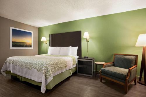a hotel room with a bed and a chair at Days Inn by Wyndham Hardeeville/ I-95 State Line in Hardeeville