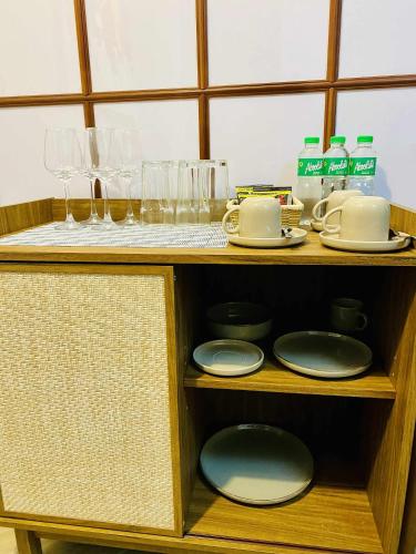 a wooden shelf with plates and glasses on it at Okaeri Place - One Regis in Bacolod