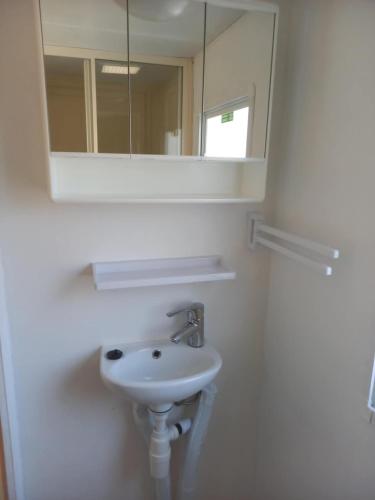 a white bathroom with a sink and a mirror at stacaravan nr16 is 5 persoons in Schoonloo