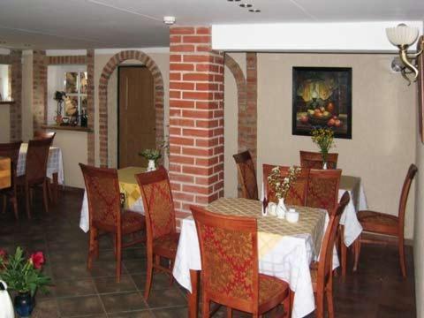 uma sala de jantar com mesas e cadeiras e uma parede de tijolos em Vila Elvyra em Nida