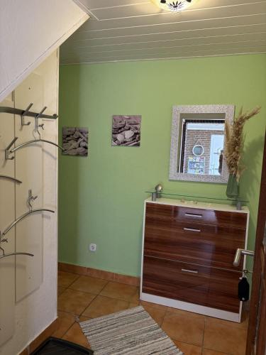 a bathroom with green walls and a wooden dresser at Golfhues-Simone-EG-Appartement-mit-grossem-Garten in Wulfen auf Fehmarn