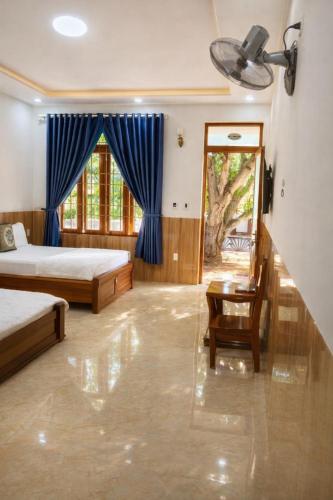 a bedroom with two beds and a table and a window at Sơn Hiển Homestay in Cam Lâm
