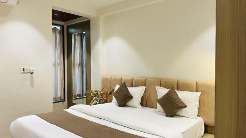 a bedroom with a large bed with white sheets and pillows at Hotel Vilaasitaa inn Ujjain in Ujjain