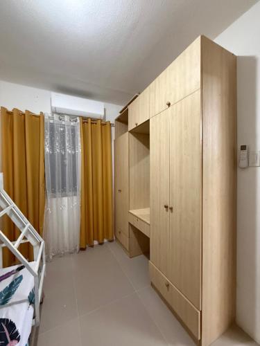 a bedroom with a wooden cabinet and yellow curtains at Private Cozy Home in Tagum