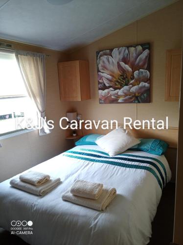 a bedroom with a bed with towels on it at K&J's Caravan Rental in Kinmel Bay